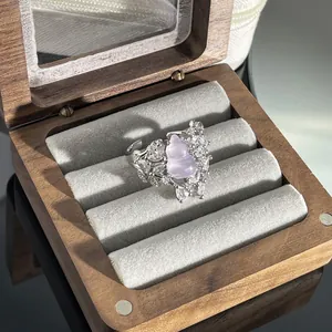 Nahaufnahme eines lila Kürbis-Rings mit Kristallen in einer hölzernen Schmuckbox.