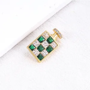 Detailopname van een vergulde parfumflesje broche met groene en heldere zirkonia's
