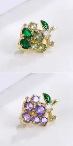 Close-up of grape-shaped brooches with purple and green crystals in gold setting.