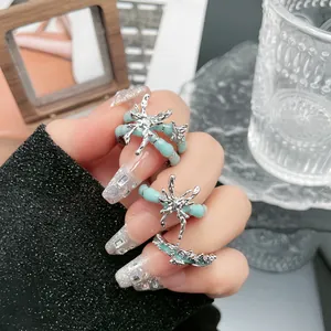 Nahaufnahme von punkigen, minzgrünen Emaille-Ringen mit flüssigem Silber-Schmetterling
