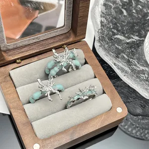Detail offener Punk-Ringe mit flüssigem Schmetterling und minzgrüner Glasur im Holzbox