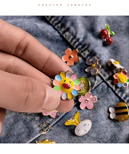 Detailed view of colorful enamel sunflower pin and cute animal brooches on denim