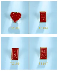 Detail of four red enamel pins featuring heart and character designs on blue background.
