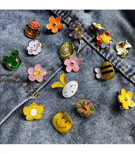 Assortment of cute colorful enamel lapel pins displayed on denim fabric background