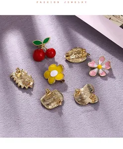 Close-up of various cute alloy enamel brooches featuring cherry and flower motifs.