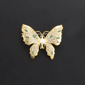 Elegant butterfly brooch with gold plating, green crystals, and central pearl for suits