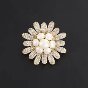 Elegant gold-tone flower brooch featuring center pearls and sparkling rhinestone petals