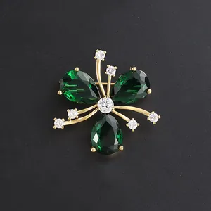 Elegant gold floral brooch pin with green teardrop gemstones and shimmering white crystals