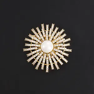 Luxury gold sunburst brooch featuring a center pearl and sparkling crystal pavé accents