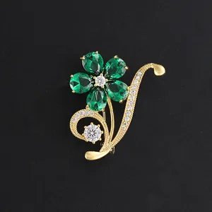 Elegant gold flower brooch with pear-cut emerald green stones and white crystal accents