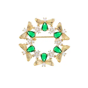 Vintage bee wreath brooch with green pear-shaped gemstones and white crystals.