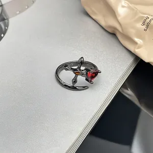 Makrodetail eines schwarzen Gothic-Rings mit rotem Herz-Edelstein und Kreuzdesign