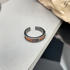 Detail eines schwarzen Punk-Rings mit orangefarbenen Steinen und einem Kleeblatt-Motiv.
