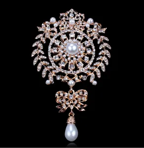 Detailed view of an ornate gold crystal brooch with pearls and water drop pendant.