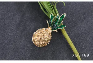 Gedetailleerde weergave van een elegante ananasbroche met kristallen en groen emaille
