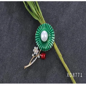 Close-up van groene bloemenbroche met parel- en kristalaccenten op grijze basis