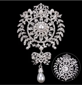 Exquisite close-up of silver crystal brooch featuring teardrop pearl and bow detail