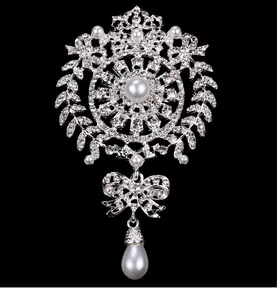 Detailed macro view of an ornate silver crystal brooch with elegant pearl pendants.