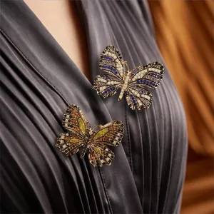 Eleganti spille a farfalla in lega con strass colorati su un abito grigio a pieghe