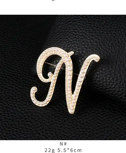 Macro view of a gold-toned letter N brooch adorned with lustrous white pearls.