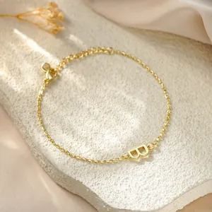 Macro view of gold titanium steel bracelet featuring a minimalist B initial charm