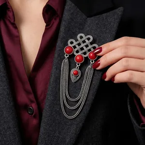 Ethnic style silver knot brooch with red stones and dangling multi-layer chains on a blazer.