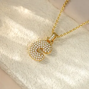 Macro detail of a gold-plated hip hop initial C pendant encrusted with sparkling crystals.
