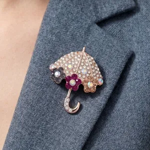 Spilla a ombrello scintillante con fiori e strass colorati su una giacca blazer