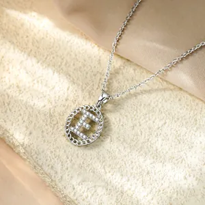 Primo piano di un'elegante collana argentata con ciondolo a lettera E in zirconi micro-pavé