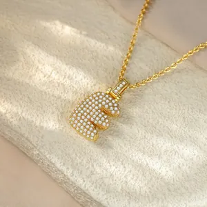Macro view of a gold-plated iced-out letter E pendant necklace with sparkling crystals.