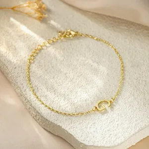 Close-up of golden titanium steel bracelet featuring a minimalist letter G charm detail.