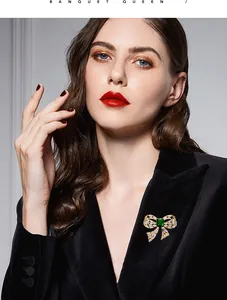 Detail view showing an elegant bow brooch with green zircon on a black velvet blazer