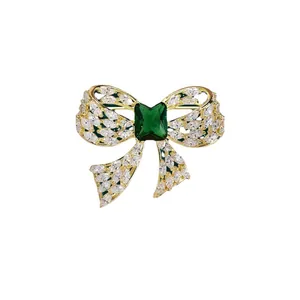 Elegant gold bow brooch with emerald green center zircon for stylish sweater accents