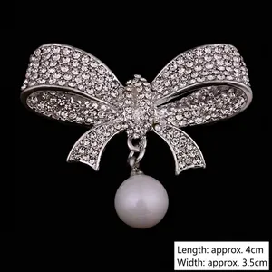 Elegant bow brooch with sparkling white rhinestones and a dangling round pearl drop