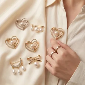 Elegant pearl and rhinestone brooches with heart and bow designs on beige shirt