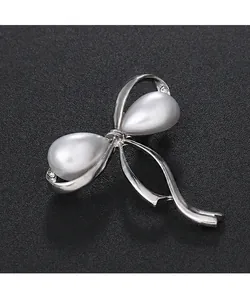 Detailansicht einer silbernen Schleifenbrosche mit Tropfenperlen und Strass