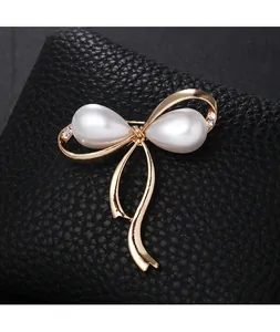 Eleganter goldener Schleifen-Brosche mit Perlen und funkelndem Strass auf schwarzem Leder.