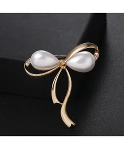 Nahaufnahme einer eleganten goldenen Schleifenbrosche mit Perlen und Kristallen