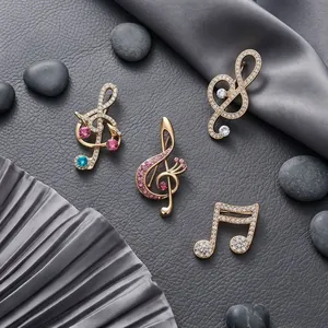 Luxury gold music note brooches with pavé rhinestones on elegant gray background
