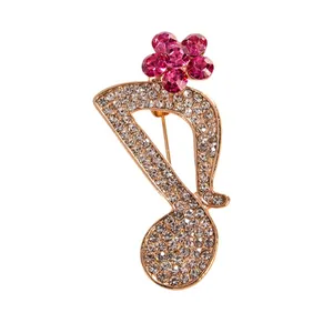 Elegant gold-tone musical note brooch with white rhinestones and pink crystal flower