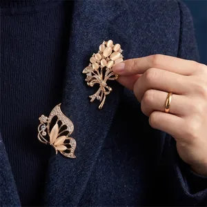 Elegant cat-eye stone brooches set in butterfly and bouquet designs on a navy blazer.