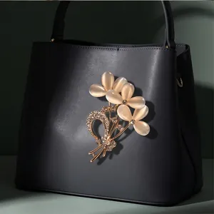 Elegant floral cat's eye stone brooch with sparkling crystals pinned on a dark grey handbag