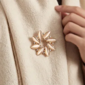 Elegant sunburst floral brooch with cat-eye stones and crystals on soft beige knitwear