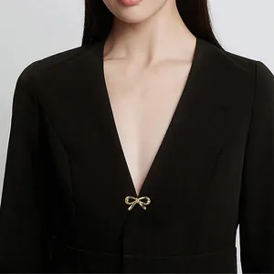 Elegant golden metal bow-shaped brooch pin as a functional accessory for women's black blazer