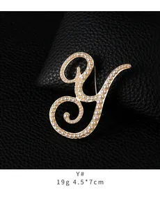 Detail view of a gold-tone pearl-studded letter Y brooch on black leather.