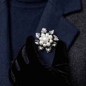 Elegant snowflake brooch with white pearls pinned to a classic navy blue wool coat collar.