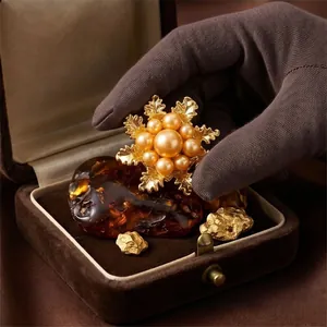 Elegant gold-tone camellia flower brooch with pearls displayed in a vintage jewelry box