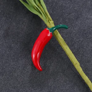 Levendige rode chilipeper broche met glanzende emaille op een donkere achtergrond