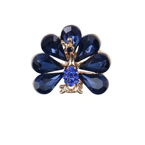 Elegante pauwenbroche met donkerblauwe druppelkristallen in een goudkleurige zetting