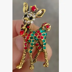 Detailed close-up view of a gold-tone deer brooch inlaid with red and green rhinestones.